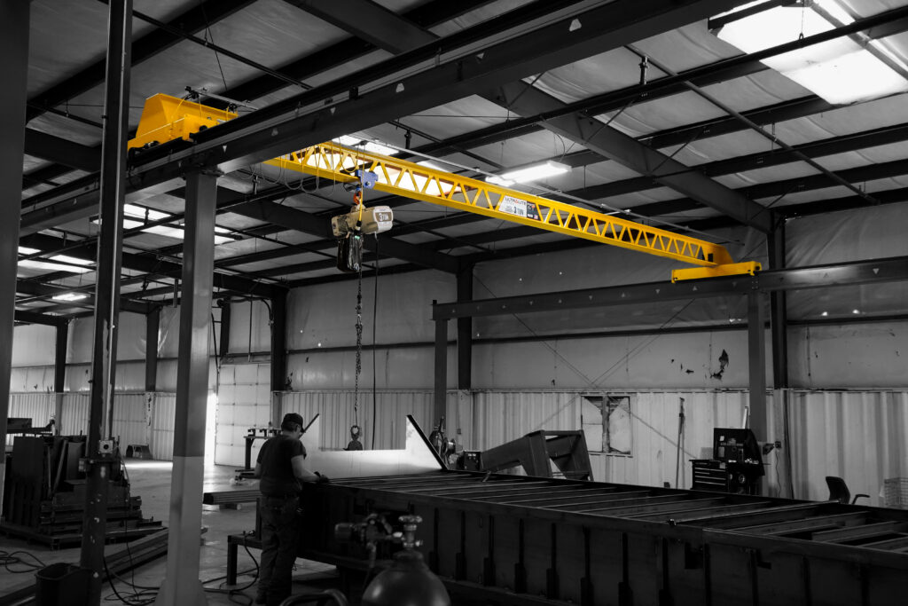 man operating 3 ton pwi ultralite crane in trailer manufacturing setting 1